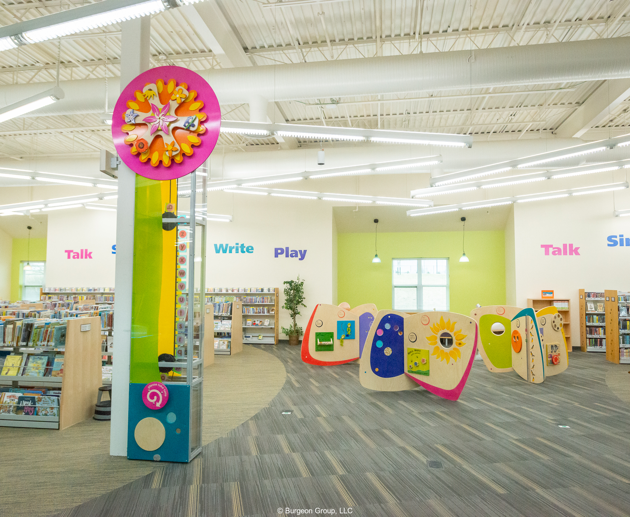 View of children's area of HCLS Glenwood Branch, featuring bright, colorful tall whirligig and three play stations.
