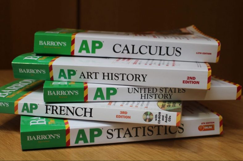 A skewed stack of AP test preparation books for calculus, art history, US History, French, and statistics.